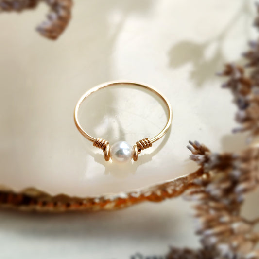 Gold ring with a pearl on a textured surface